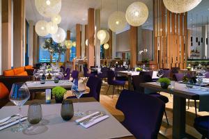 モンペリエにあるコートヤード バイ マリオット モンペリエのテーブル、紫色の椅子、シャンデリアが備わるレストラン