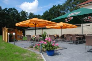 un patio avec des parasols, des tables et des chaises avec des fleurs dans l'établissement Gasthaus-Witte, à Wallenhorst
