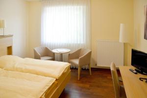 1 dormitorio con cama, mesa y TV en Gasthaus-Witte, en Wallenhorst