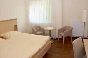 1 Schlafzimmer mit einem Bett, 2 Stühlen und einem Tisch in der Unterkunft Gasthaus-Witte in Wallenhorst