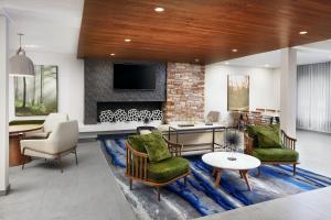 a living room with chairs and a fireplace at Fairfield Inn & Suites Worcester Auburn in Auburn