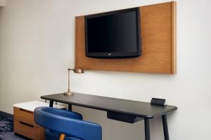 a room with a desk and a tv on a wall at Fairfield Inn & Suites Worcester Auburn in Auburn