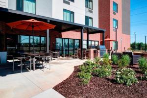 a patio with an umbrella and tables and chairs at TownePlace Suites by Marriott Macon Mercer University in Macon