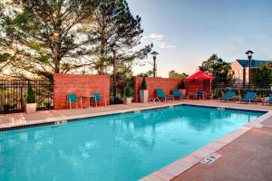 a swimming pool with blue chairs and a brick wall at TownePlace Suites by Marriott Macon Mercer University in Macon