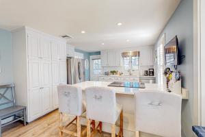 cocina con armarios blancos, mesa y sillas en Little River Manor, en Cotuit