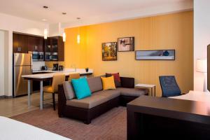 a living room with a couch and a kitchen at Residence Inn by Marriott Calgary South in Calgary