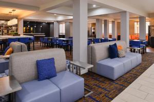 eine Lobby mit Sofas, Tischen und blauen Stühlen in der Unterkunft Courtyard by Marriott Milwaukee North/Brown Deer in Brown Deer