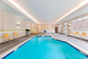 uma piscina num quarto de hotel com cadeiras e uma piscina em Fairfield Inn & Suites by Marriott Pittsburgh Airport/Robinson Township em Robinson Township