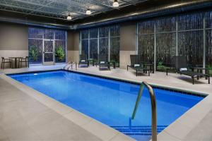 uma piscina num quarto de hotel com cadeiras e mesas em AC Hotel By Marriott Portland Beaverton em Beaverton