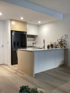 uma cozinha com armários brancos e um frigorífico preto em In the Heart of Port Melbourne em Melbourne