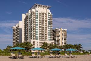 ein Hotel mit Liegestühlen und Sonnenschirmen am Strand in der Unterkunft Marriott's Oceana Palms in Palm Beach Shores