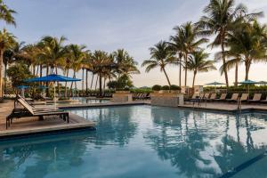 - une piscine dans un complexe avec des palmiers dans l'établissement Marriott's Oceana Palms, à Palm Beach Shores