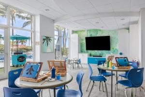 una sala de estar con mesas y sillas y TV de pantalla plana. en Marriott's Oceana Palms en Palm Beach Shores