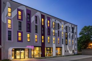 a large white building with illuminated windows at night at Moxy Simmern in Simmern