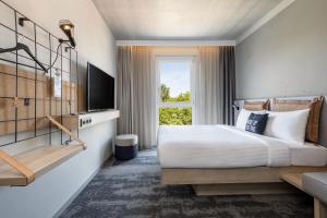 a hotel room with a bed and a television at Moxy Simmern in Simmern