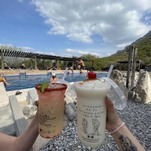 two people holding drinks in front of a pool at La Posada en el Potrero Chico in Hidalgo