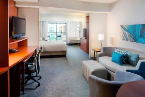 Courtyard by Marriott San Antonio SeaWorld®/Westover Hills في سان انطونيو: غرفة في الفندق مع مكتب وغرفة مع سرير وأريكة