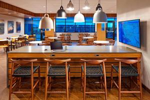 a large wooden bar with chairs and a laptop on it at Fairfield by Marriott Inn & Suites Indio Coachella Valley in Indio