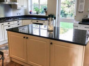 a kitchen with a large island with black counter top at Peach Cottage in Wool