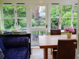 a dining room with a table and chairs and windows at Peach Cottage in Wool