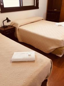 two beds in a hotel room with a towel on the bed at Porto Rei Residence Hotel in Rio Grande