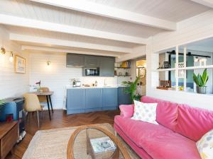 a living room with a pink couch and a kitchen at The Cosy Cabin in Clapton in Gordano