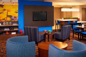 a restaurant with blue chairs and tables and a tv at Courtyard Toledo Maumee/Arrowhead in Maumee