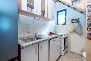 a small kitchen with white cabinets and a sink at Secluded fisherman's cottage Cove Soline, Pasman - 8222 in Kraj