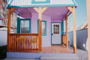 Agave Tiny House at Cactus Flower-HOT TUB-Pet Friendly-No Pet Fees! في ألباكيركي: منزل على سطح أرجواني وكراسي على سطح