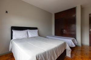um quarto com 2 camas com lençóis brancos e uma janela em Apart Budapest - Conforto na melhor Rua de Águas de Lindóia em Águas de Lindoia