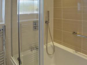 a shower with a glass door next to a bath tub at 4 Eldin Hall Cottages in Cayton