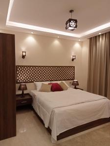 Relax Guest House في السادس من أكتوبر: غرفة نوم بسرير ابيض كبير ومصباحين