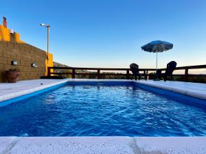 una piscina con sillas y sombrilla en Palotes Sierras Cabañas, en Villa Giardino