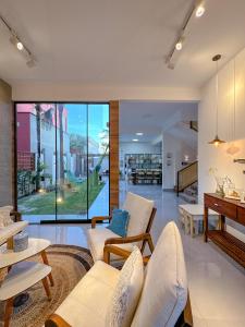 un soggiorno con mobili bianchi e una grande finestra di Casa do Sino - Casa de família nos Lençóis Maranhenses! a Barreirinhas