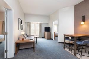 a hotel room with a bed and a desk and a table at Residence Inn by Marriott Williamsburg in Williamsburg
