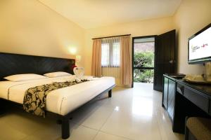 a bedroom with a bed and a flat screen tv at Legian Paradiso Hotel in Legian