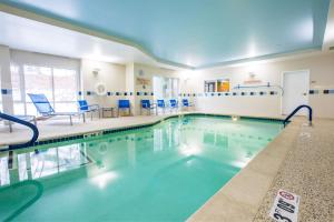 una piscina con sillas azules en un edificio en TownePlace Suites by Marriott Gilford, en Gilford