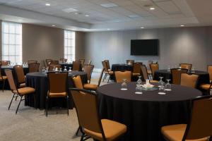 una sala de conferencias con mesas, sillas y una pantalla en SpringHill Suites by Marriott New Orleans Warehouse Arts District en Nueva Orleans