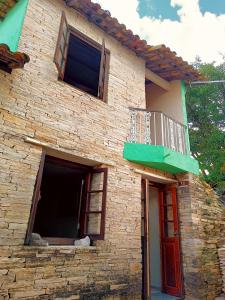 Casa de ladrillo con 2 ventanas y balcón en Suites em São Thomé das Letras, en São Thomé das Letras