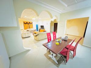 a living room with a wooden table and red chairs at West Coast Apartments Brufut Wullingkama GM in Mariama Kunda