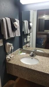 een badkamer met een wastafel, een spiegel en handdoeken bij OSU 2 Queen Beds Hotel Room 136 Wi-Fi Hot Tub Booking in Stillwater