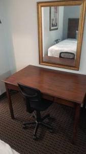 een houten bureau met een stoel voor een spiegel bij OSU 2 Queen Beds Hotel Room 136 Wi-Fi Hot Tub Booking in Stillwater