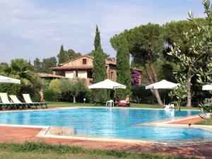 a swimming pool in front of a house with umbrellas at Fattoria Cirene in Follonica