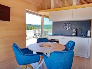 uma cozinha com uma mesa de madeira e cadeiras azuis em Eco-friendly detached tiny house in the Black Forest on huge property 