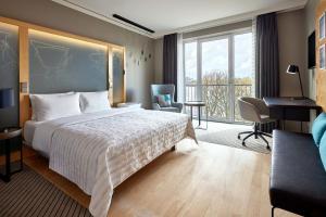 a hotel room with a bed and a desk and a window at Le Méridien Hamburg in Hamburg