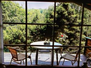 ein Tisch und zwei Stühle auf einer Veranda mit einem Fenster in der Unterkunft Ortho Hideaway with Garden in Bertogne