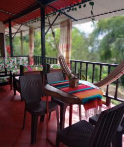 - une table et des chaises sur une terrasse couverte avec un hamac dans l'établissement La Flor de Jalisco, à Calarcá