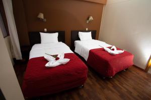 two beds in a hotel room with white towels on them at Kapac Inn Hotel in Cusco