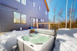una bañera de hidromasaje en la nieve frente a una casa en On Mountain Time, en Carrabassett