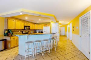 a kitchen with yellow cabinets and bar stools at Bahia Vista I 204 in Ocean City